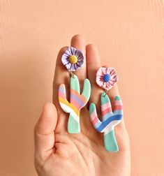 a person is holding two flower clips in their hand, one has a pink and blue flower on it