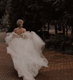 a woman in a white dress is walking down the street with her back to the camera