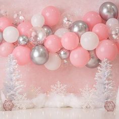 balloons and snowflakes are hanging from the ceiling in front of a pink wall