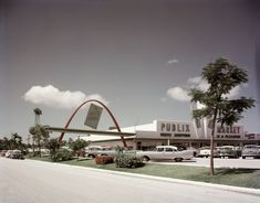 an old photo of the outside of a building with cars parked in front of it