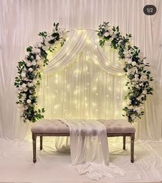 a wedding ceremony setup with white flowers and greenery on the back of a bench