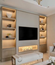 a modern living room with built in shelving units and a flat screen tv mounted on the wall