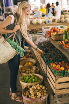 a woman is shopping for vegetables at an outdoor market