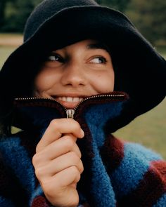 a woman wearing a blue and red jacket with a black hat on top of her head