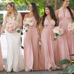 a group of women standing next to each other holding bouquets and smiling at the camera