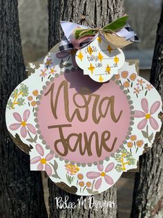 a pink and white sign hanging from the side of a tree