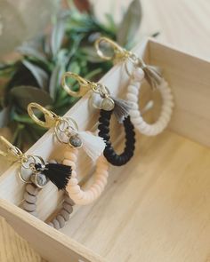 four pairs of tasseled keychains in a wooden box on a table