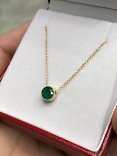 Featured here is a stunning, round Colombian emerald pendant in fine 14k yellow gold. Displayed in the center is a medium-green emerald accented by a simple bezel gold mount. The earth mined, green emerald has a desirable lush green color. This emerald is 100% earth mined and is not perfect! Gorgeous flaws are seen within the stone, embrace uniqueness! The chain is attached to this piece, non-removal. Total Carat Weight: 0.90cts Setting Style: Bezel Setting Material: 14K Yellow Gold Main Stone: Elegant Gold Emerald Necklace, Yellow Gold Emerald Necklace With Round Pendant, Gold Emerald Necklace With Round Birthstone, Elegant Emerald Pendant Necklace With Bezel Setting, Elegant Emerald Necklace With Round Pendant, Elegant Emerald Round Pendant Necklace, Elegant Emerald Birthstone Necklace With Round Pendant, Yellow Gold Solitaire Necklace With Gemstone Pendant, Gold Dainty Emerald Necklace