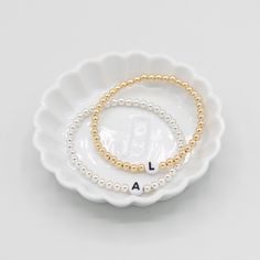 One of our classics from the beaded bliss collection with a twist. The 'name it' collection allows you to customize your bracelet with your desired initial! Customers love to wear the initials of their kids or wear their personal monogram by stacking three separate initial bracelets. The perfect piece of jewelry to create a thoughtful gift that can be worn every day. Just add your desired initial in the space above. This style is created with one of our "stretchy" cords for easy wear and effortl Elegant Jewelry With Letter Beads For Everyday, Classic Adjustable White Name Bracelet, Classic Adjustable Beaded Bracelets For Anniversary, Classic Sterling Silver Stretch Bracelet, Classic White Adjustable Name Bracelet, Elegant Hypoallergenic Name Bracelet With Round Beads, White Classic Beaded Bracelets For Everyday, Classic White Name Bracelet As Gift, Elegant White Name Bracelet With Letter Beads