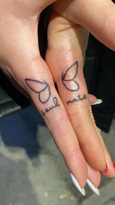 two fingers that have tattoos on them