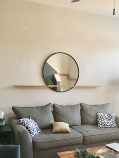 a living room with a couch, coffee table and mirror on the wall above it