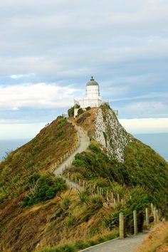 a lighthouse on top of a hill with a path going up it's side