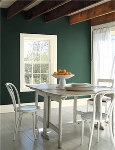 a dining room table with chairs and a bowl of fruit on top of the table