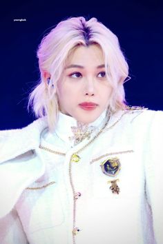 the girl with blonde hair is wearing a white coat and gold jewelry on her neck