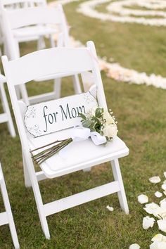 white chairs with flowers on them and a sign that says for mom sitting in the grass