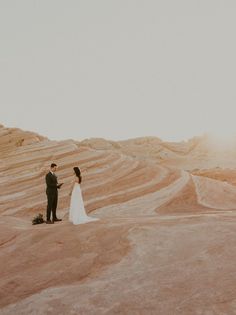 a bride and groom standing in the desert