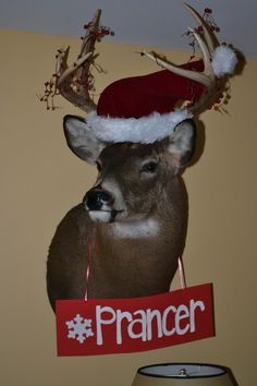 a deer head wearing a santa hat and holding a sign that says prancer