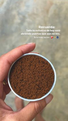 a hand holding a small bowl filled with ground coffee