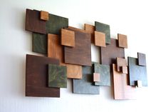 a wall sculpture made out of wood and metal squares on a white wall behind it