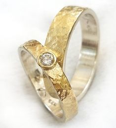 two gold wedding bands with a diamond in the middle