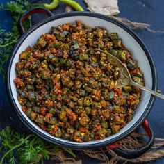 a white bowl filled with food on top of a blue counter next to green peppers