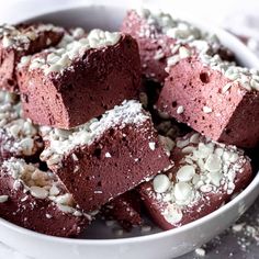 a white bowl filled with brownies covered in powdered sugar