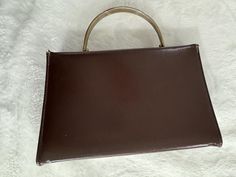 This cool vintage retro mod style 1950s solid brown fall bag still has life left in it! There are some signs of use on the exterior but lots on the interior. The interior of this bag used to be bright red satin or silk and has dulled from use. The bag is so cool though. Its s a straight for the 50s solid brass handle bag that looks great with any fall outfit. It has character for sure! This brown bag is a small rectangle with very clean lines. The brass snap closure is hidden. The closure works Retro Brown Shoulder Bag Gift, Retro Brown Shoulder Bag As Gift, Retro Brown Formal Bags, Vintage Brown Shoulder Bag For Gift, Vintage Brown Square Bag, Vintage Brown Retro Bags For Evening, Vintage Brown Handheld Bag, Brown Mid-century Bags For Formal Occasions, Retro Brown Vintage Bags