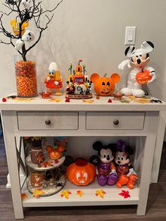 a white table topped with lots of candy and mickey mouse figurines on top of it