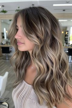 Woman with wavy, layered hair featuring ash blonde highlights and lowlights in a modern salon. Blended Lowlights Brown Hair, Very Light Brunette Hair, Beige Blonde Babylights On Dark Hair, Soft Blonde Balayage Brunettes, Light Blonde Highlights In Brown Hair, Blonde With Lots Of Lowlights, Dimensional Blonde With Lowlights Fall, Rooty Dimensional Blonde, Root Melt Dark Blonde