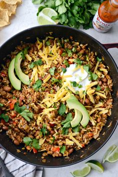 a skillet filled with mexican rice, beans and avocado garnished with sour cream