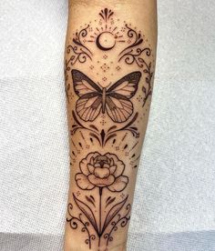 a tattoo on the leg of a person with a butterfly and flower design around it