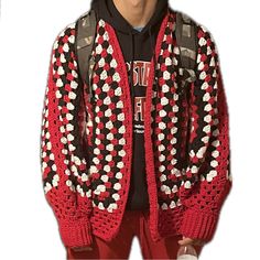 a man wearing a red and black sweater with white flowers on the sleeves is standing in front of a white background