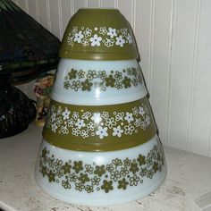 three tiered green and white vase sitting on top of a counter next to a lamp