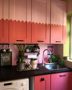 this kitchen has pink cabinets and black counter tops, along with a white dishwasher