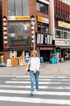 a woman is crossing the street in front of buildings