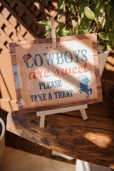 a sign that says cowboys are sweet please take a treat on a wooden table next to a potted plant