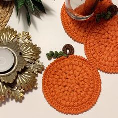 three crocheted pumpkin coasters sitting on top of a table