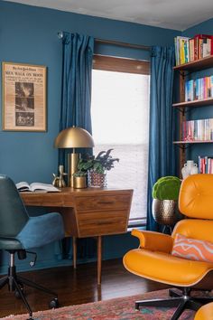 an office with blue walls and orange chairs in front of a desk, bookshelf, and window