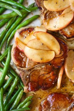 some green beans and meat on a plate with apple slices, onions and seasoning