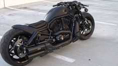 a black motorcycle parked in a parking lot next to a building with no people on it