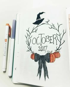 an open notebook with the words october written on it and pumpkins in front of it