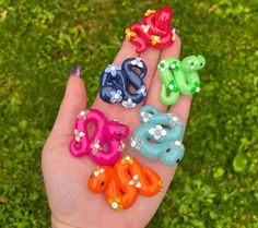 a person's hand holding five different colored plastic letters in the shape of animals