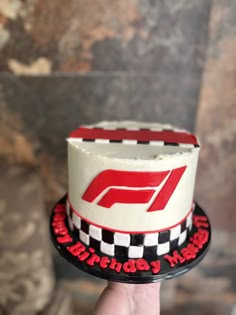 a hand holding up a cake with the number five on it and checkered design