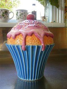 a cupcake covered in frosting sitting on top of a table next to a window