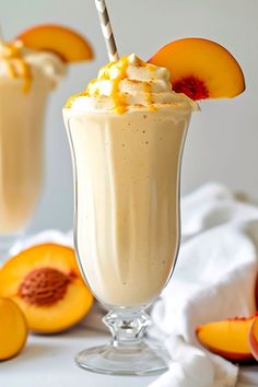 two glasses filled with ice cream and topped with sliced peaches on a white surface