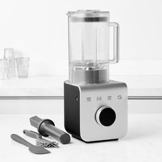 a blender sitting on top of a counter next to utensils