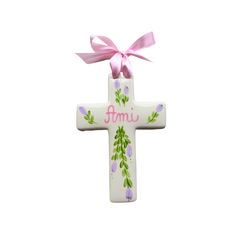 a ceramic cross with pink ribbon and flowers on the front is hanging from it's side