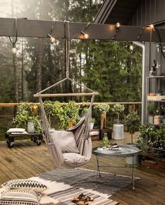 a hammock chair on a deck with lights strung from the ceiling above it