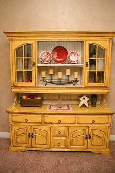 a yellow china cabinet with plates on top