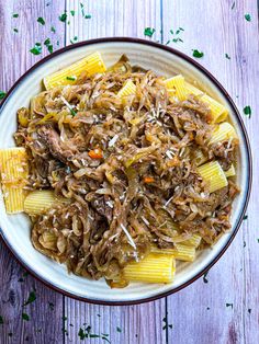 a bowl filled with pasta and meat on top of a wooden table